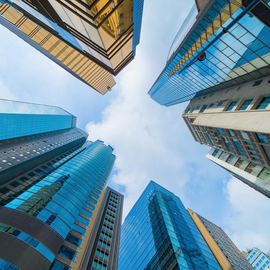 Looking up to high-rise office buildings, skyscrapers, architectures in financial district. Smart urban city for business and technology concept background in Downtown Hong Kong, China.